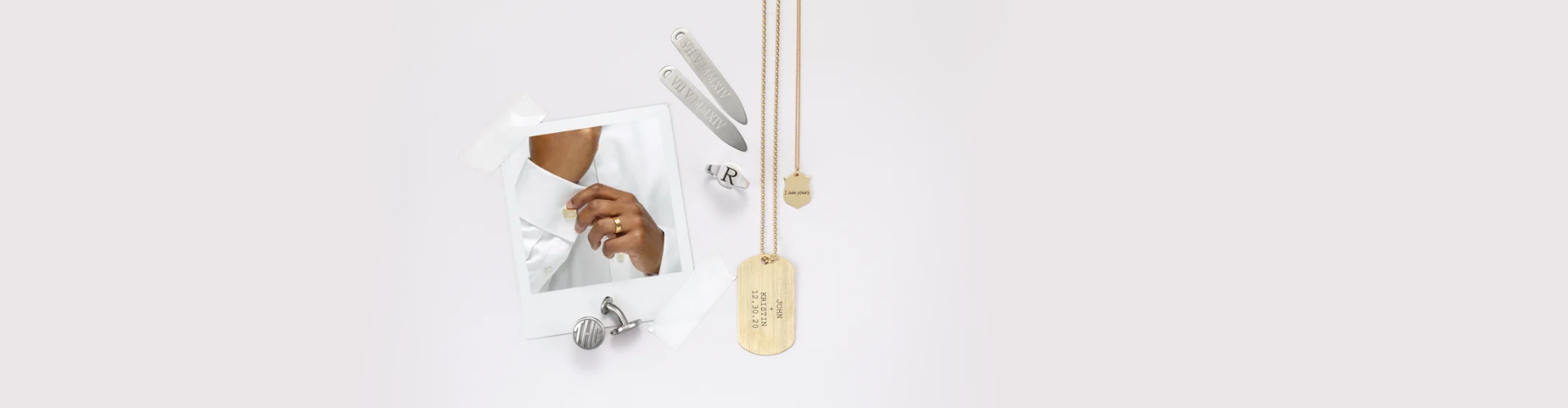 Hands of a man in a Polaroid photo fixing his cufflink while wearing a yellow gold wedding band. The photo is taped to a surface, alongside several pieces of jewellery, including: custom monographed white gold cufflinks, as well as custom engraved stainless steel collar stays. ayelllow gold pendant and dog tag, and an initial silver signet ring.