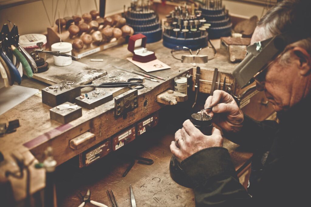 Professional jeweller repairing jewellery at a workbench.